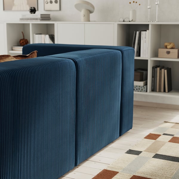 A deep blue modular sofa with a footrest, under-seat storage, and a geometric rug. The sofa is designed for comfort and practicality.