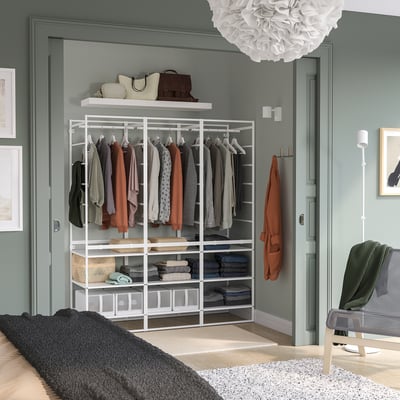Wardrobe system in bedroom, featuring clothes, bags, and shelves against blue walls.