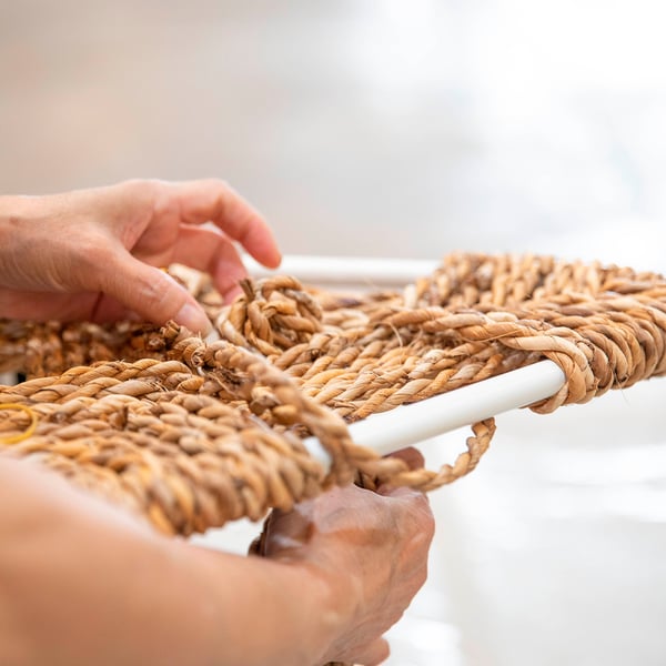 Hands assemble woven banana fibre stool, showcasing craftsmanship and durable materials.