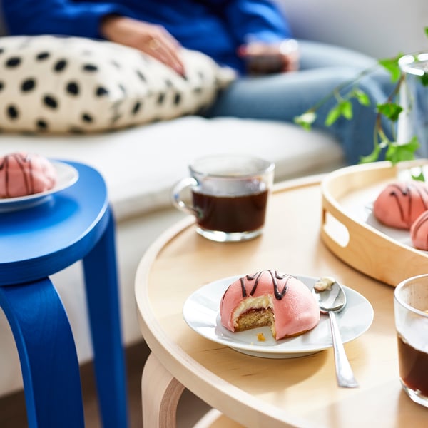 A cosy setup with pink cream cakes, coffee, and comfortable seating for socialising.