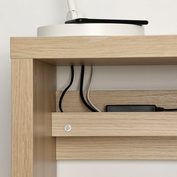 Wooden desk with built-in cable outlet, showing organised cables behind shelves.