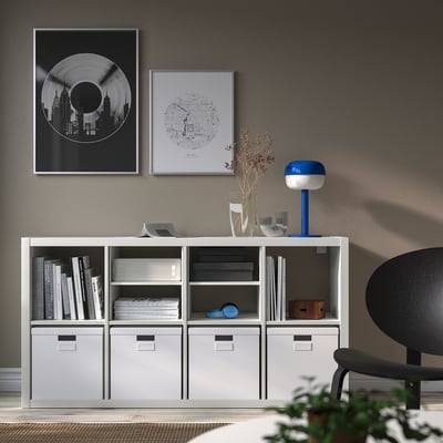 Modern room with KALLAX shelves filled with books and decorations, blue accent lamp, minimalistic and functional.
