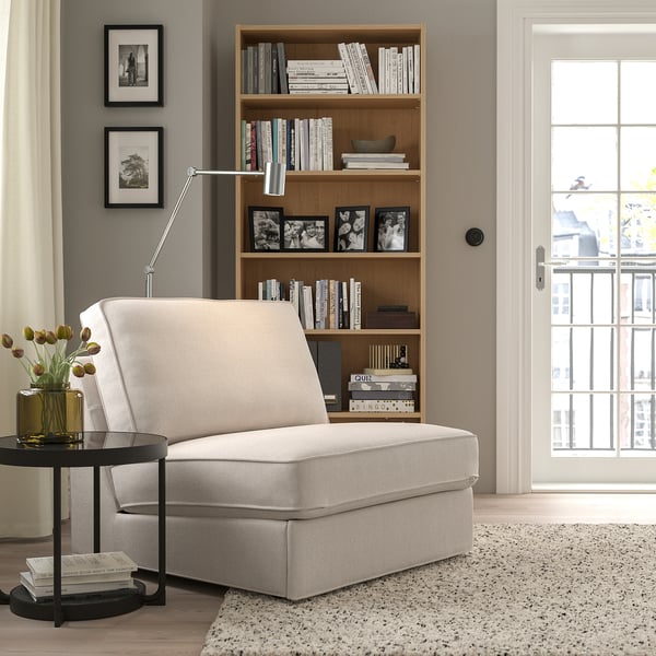 Modern living room with white KIVIK sofa-bed, bookshelf, and minimalist lamp.