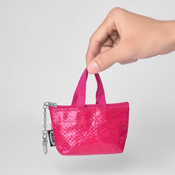 Small bright pink bag held by hand, featuring a zip, two handles, and a keychain attachment. Ideal for coins and small items.