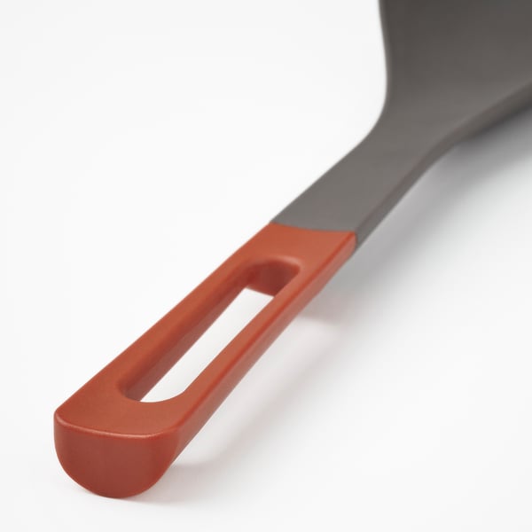 Close-up of red silicone-edged utensil handle, firmly attached to metal spoon, showcasing durable and ergonomic design.