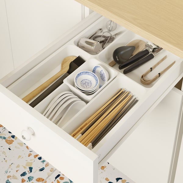 White kitchen drawer with organised utensils and plates, part of IKEA KNOXHULT modular setup.