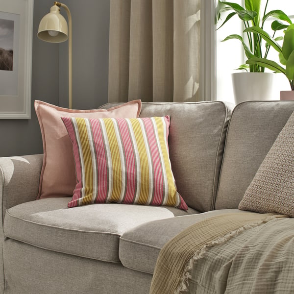 Striped cushion on sofa, pink, yellow, white stripes. Beige sofa frame, soft fabric cover with zip.