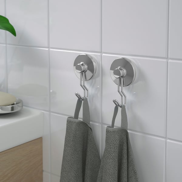 Two metallic hooks with suction cups hang grey towels on tiled wall, showcasing their strong hold and space-saving design.
