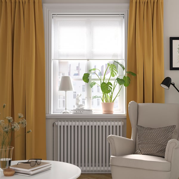 Cosy reading nook with huge window, green plant, grey armchair, and mustard curtains.