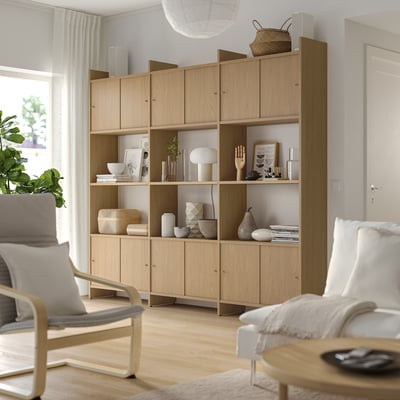 Large wooden bookshelves with light-colored decor, including books, vases, and a chair, providing a minimalist and organised space.