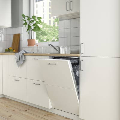 Modern white kitchen with open dishwasher, smaller than cabinets.