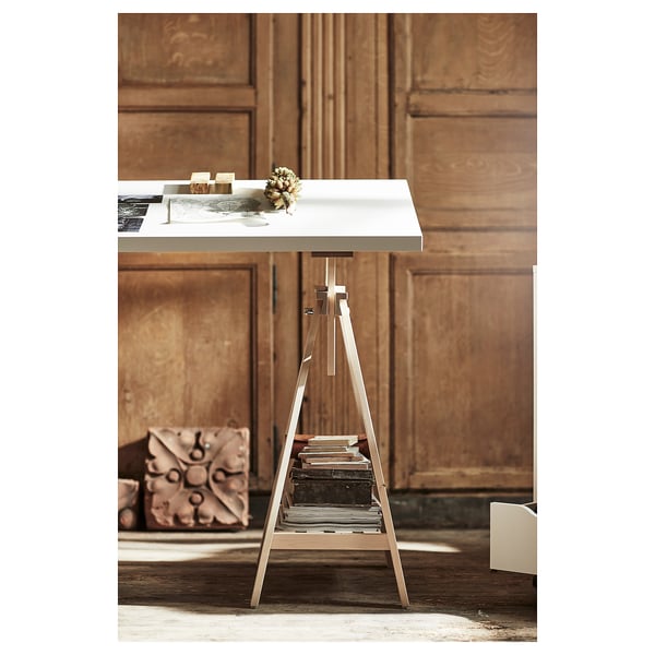 A sleek, modern white desk with a metallic trestle, featuring a minimalist design. The tabletop sits atop a sturdy, slim frame with built-in shelves.