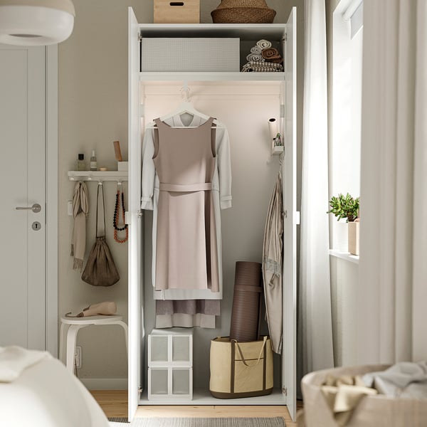 Open wardrobe with hanging dress and folded clothes, shelves, and storage cubes.