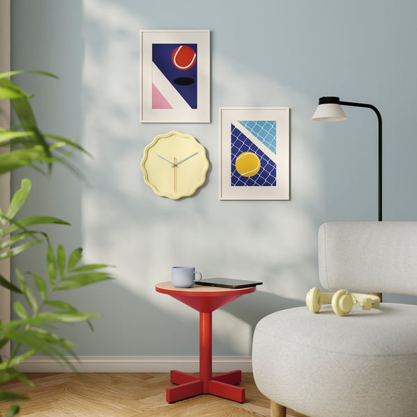 Modern living room with round yellow clock, art, white chair, and green plant.