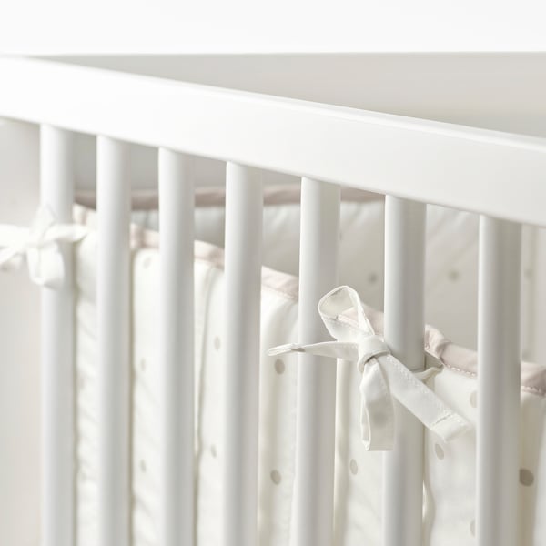 White baby crib bumper with bow. Protects baby from hitting bed slats.