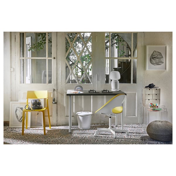 Bright home office with LINNMON yellow desk and grey chair, white accessories, large window, and abstract art.