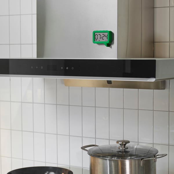Small green LJUNGPIPARE clock magnet on stove, easy to read.
