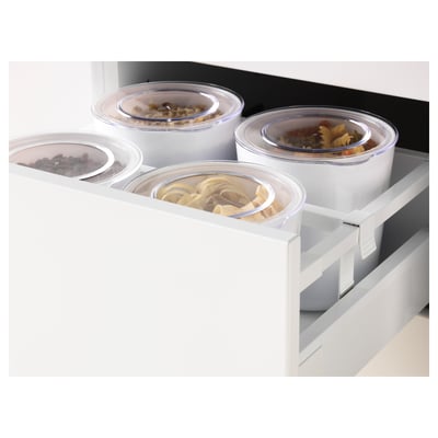 Four clear plastic containers with lids, filled with different food items, stored inside a fully extendable drawer.