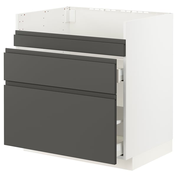 A white METOD kitchen cabinet with dark grey voxtorp drawer fronts. It three drawers and a base for built-in appliances or a sink.