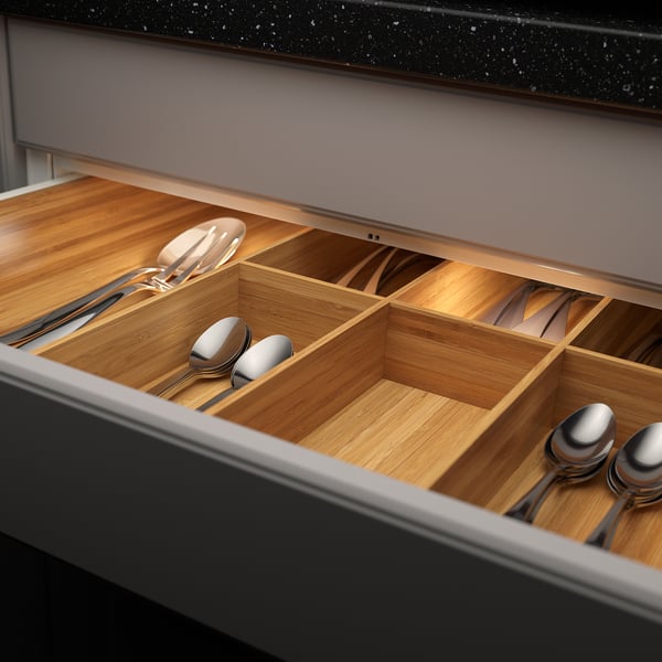 Wooden drawer organiser with built-in led, lighting up kitchen utensils in compartments.