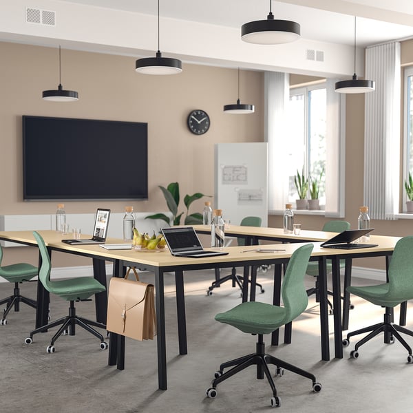 Modern conference room with green chairs, light tables, laptops, and large windows.