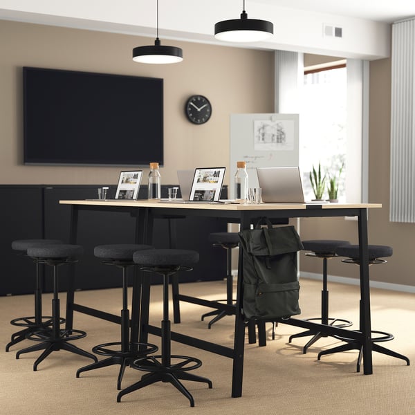Modern office setup with MITTZON conference table, laptop, and backpack.