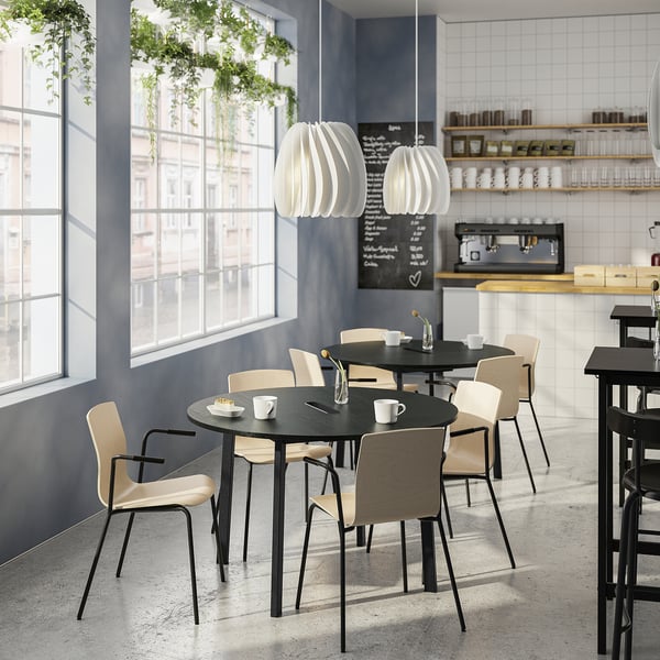 Modern café with light chairs, bright windows, compact tables, chalkboard menu.