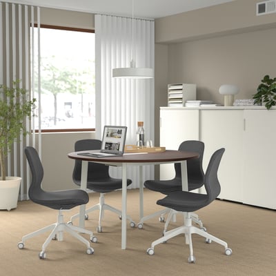 Modern minimalist meeting area with MITTZON table, dark chairs, white cabinet, large window, and plants.