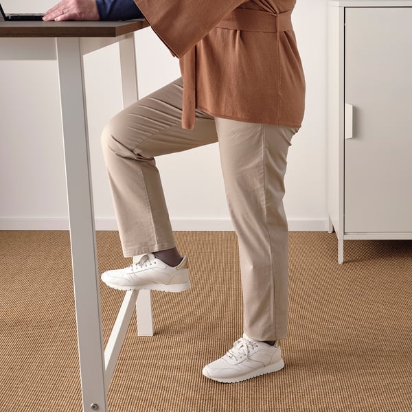 Person using footrest while working at a high table, promoting active sitting or standing.