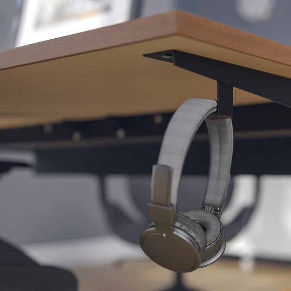 Wireless headphones hang on MITTZON desks side hook, showing practical storage feature.