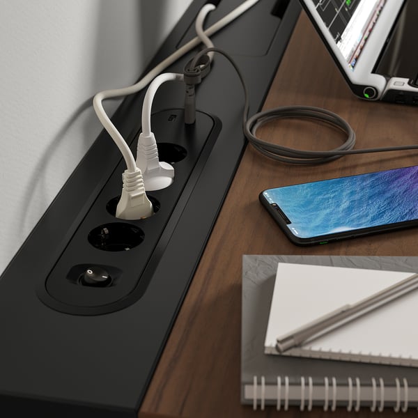 Desk with power sockets and cable tray. Phone and notebook on top.