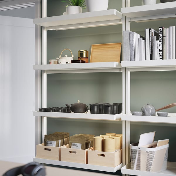 White MITTZON shelving unit with various items. Includes stacks of boxes, teapots, cups, and books on four shelves.