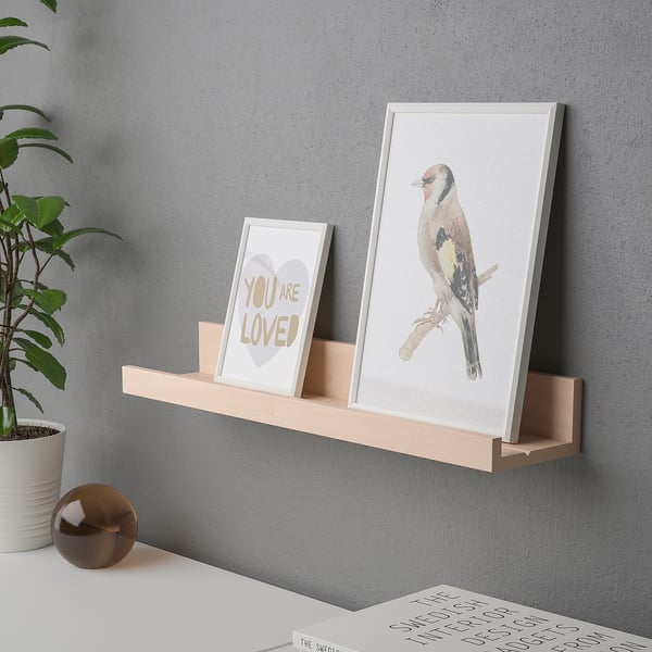 Wall shelf displaying framed art, showing functional groove for small frames.