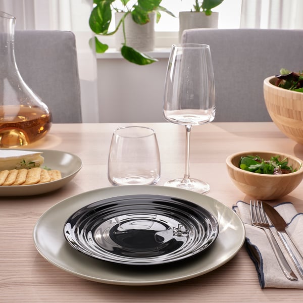 A wooden table set with NÄTBARB glass dinnerware, including plates, wine glasses, and bowls, arranged neatly with cutlery.