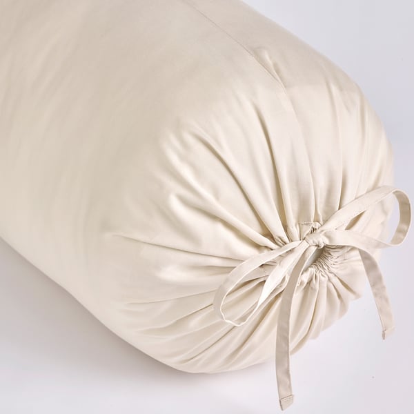 Elegant cream-colored bolster cushion with smooth, lustrous fabric, tied neatly with satin ribbon ends. Luxurious and inviting.