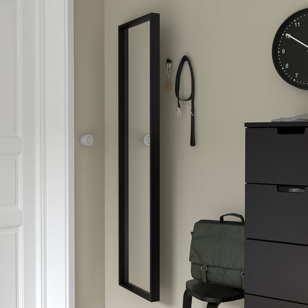 Mirror with keys and lanyard hooks, reflecting clock.