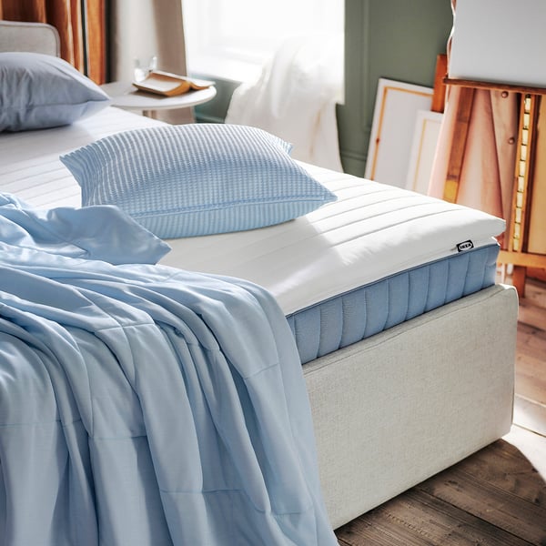 A NJÅSATS pillow, light blue, waffle-weave, 100% recycled materials. Small, fits well with bedding.
