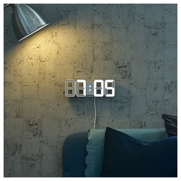 NOLLÅTTA clock on grey wall, time 8:89, with pillow.