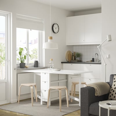 Modern kitchen with white NORDEN table and stools, black accents, and large window.