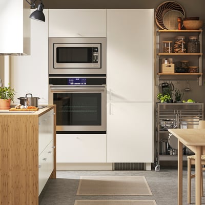 Modern kitchen with built-in stainless steel oven and microwave, wooden counter, and organised shelves.