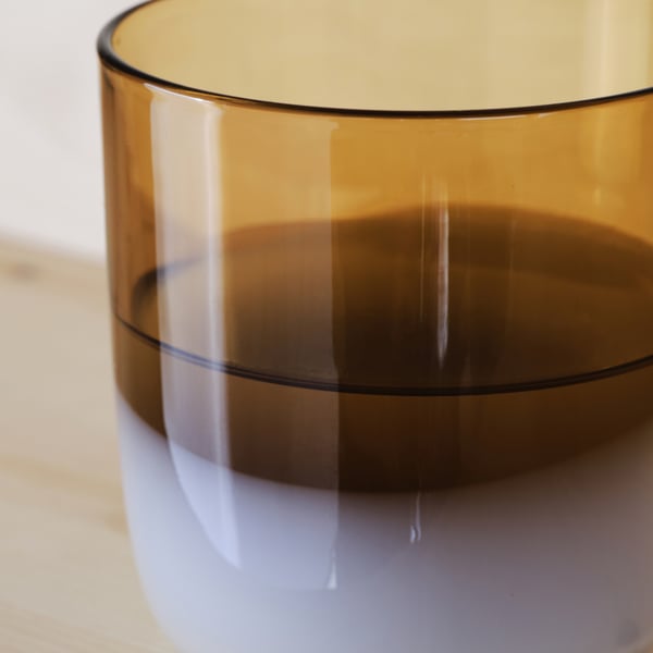 Amber glass cup, mouth-blown, with clear, smooth edges, resting on a wooden surface.
