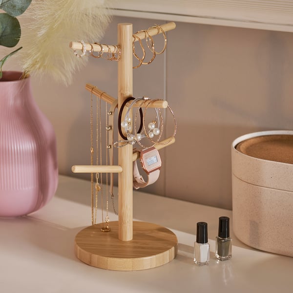 Bamboo jewellery stand with necklaces, bracelets, rings, and watch.