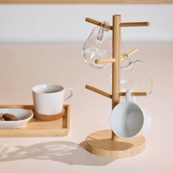 Bamboo mug tree with three mugs: one glass, one white, one blue. Includes a serving tray with small bowls.