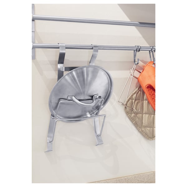 Metal lid organiser on counter, with orange utensil holder.