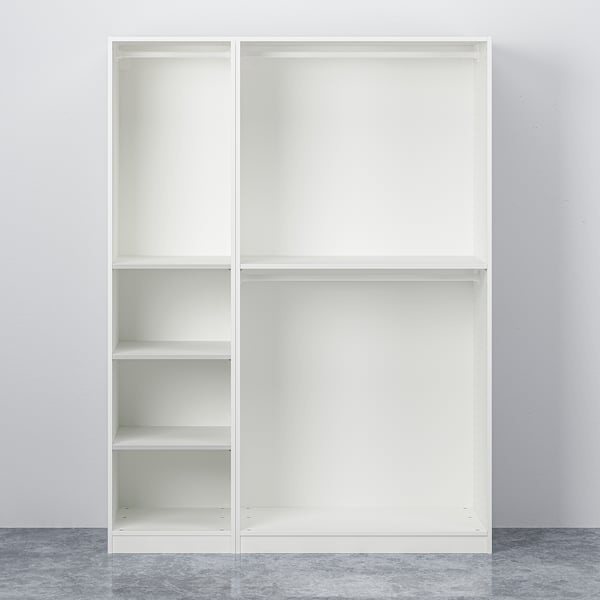 White PAX wardrobe with adjustable feet, closed doors, and empty shelves against a grey wall and floor.