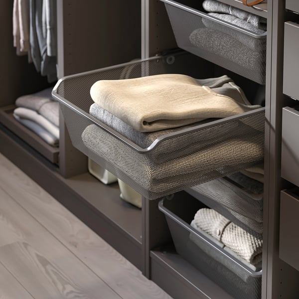 Wire basket filled with folded beige towels in organised wardrobe.