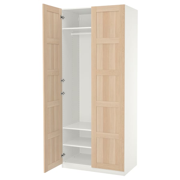 A white and light wood-colored ikea PAX wardrobe with one door open, revealing a clothes rail and shelves.