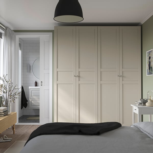 Modern bedroom with large light wardrobe, pendant light, bed, and bathroom entrance.