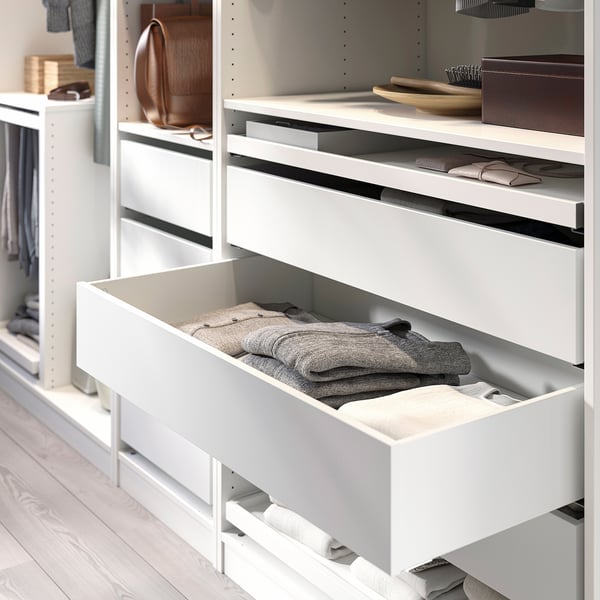 White PAX wardrobe with open drawer full of folded clothes, showing organised storage.