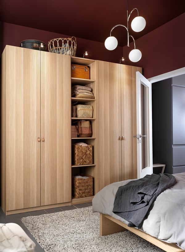 Modern bedroom with light wooden PAX wardrobe, white lights, and grey bedding.